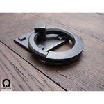 wrought iron ring pull with square backplate attached to a wooden door
