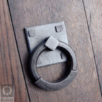 wrought iron ring pull with square backplate attached to a wooden door